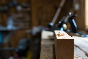 Wood chip on focus, pine board, oak worbench,  carpentry tools on the blurried background, workshop, shallow depth of field, space for text.
