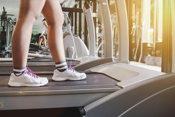 Close up shoes woman's running on treadmill. Woman with muscular legs in gym