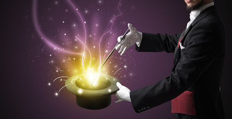 Magician hand conjure with wand  light from a black cylinder