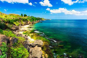 Fototapeta na wymiar Azure beach with rocky mountains and clear water of Indian ocean at sunny day / A view of a cliff in Bali Indonesia / Bali, Indonesia