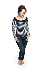 A young woman in a striped tight blouse  and round glasses stands modestly, pressing his hands to his hips. Modestly looks down