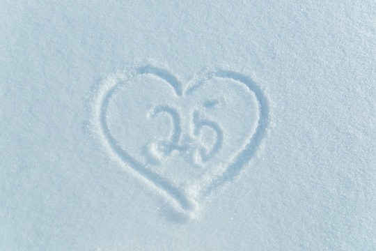A figure of twenty five written in the snow in the painted heart. Snow texture.