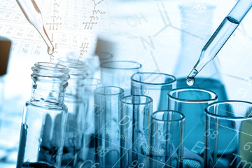 Dropping chemical liquid to test tube with lab glassware background. Science or chemistry research and development concept. 