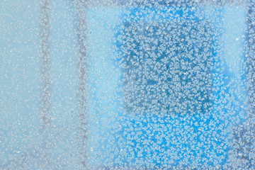 Naklejka na ściany i meble Snow crystals on blue glass.
