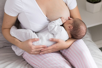 Young mother breastfeeding her newborn baby son. Happy mom hugging her babyboy. Breast feeding and lactation infant concept. - obrazy, fototapety, plakaty