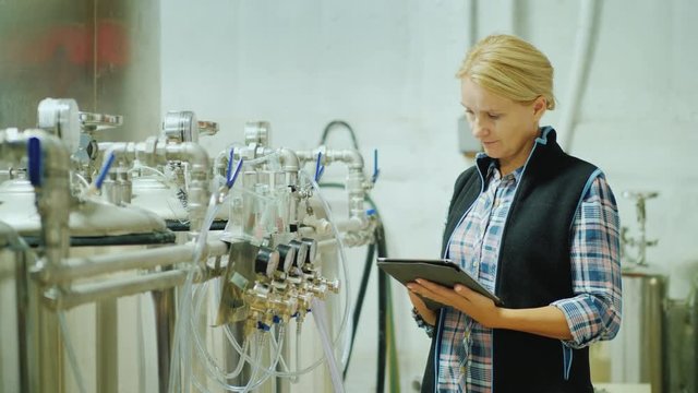 A woman with a tablet checks the work of the units in the food factory