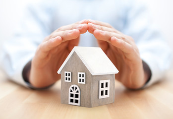 Small wooden house covered by hands 