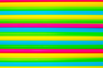 Colorful background. Vivid flatlay. Multicolored plastic drinking cocktail straws on a white background.
