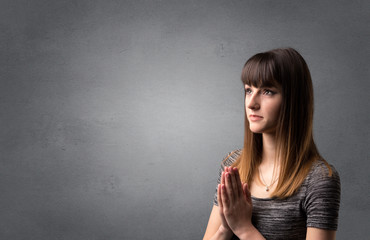 Obraz premium Young woman praying on a grey background
