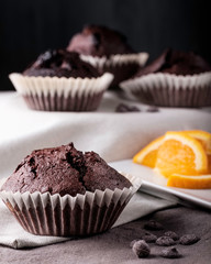 Homemade chocolate muffins with orange on dark background.