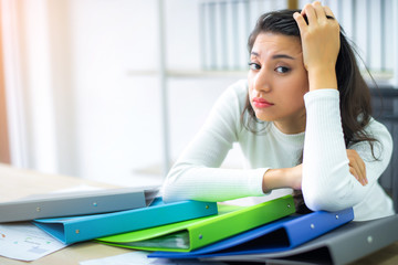 A bored business woman sitting behind a pile of files, boring work hard concept. 