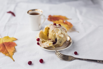 a cup of coffee, cinnamon bun and yellow leaves