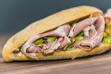 Fresh baguette sandwich on wooden background. Classic BLT sandwiches. Close up.