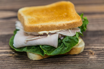 Fresh baguette sandwich on wooden background. Classic BLT sandwiches. Close up.