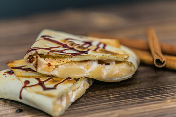 A delicious pancake with fresh fruits and chocolate, served in a wooden table.