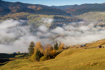 Fototapeta na wymiar Foggy morning in Bucovina. Autumn colorful landscape in the romanian village