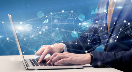 Businessman typing on laptop with linked reports charts grapghs around
