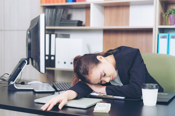 beautiful businesswoman sleeping over a laptop in a desk at work in office , business concept