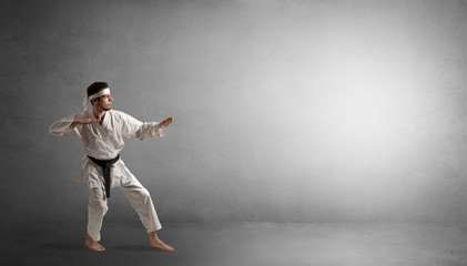 Small karate man fighting in an empty grey copy space