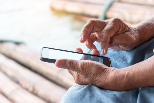 Close-up image of elderly asian woman hands holding and using smartphone typing an sms message to her friends and study their knowledge on internet. Education and Lifelong learning concept.