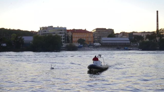 A man in a red jacket on a boat on the river, swan. Self-isolation, quarantine of viral infection COVID 19. Healthy lifestyle.