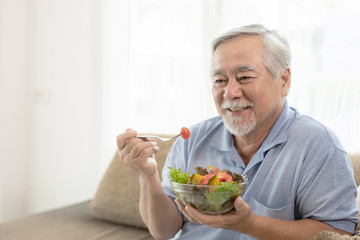 Lifestyle senior man feel happy enjoy eating diet food fresh salad on sofa