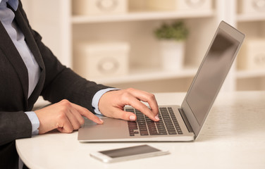 Business woman below chest working on her laptop in a cozy environment
