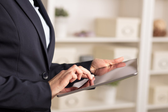 Business woman below chest using tablet in a homey environment
