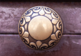 Exterior vintage door handle with a bronze finish on a brown front door