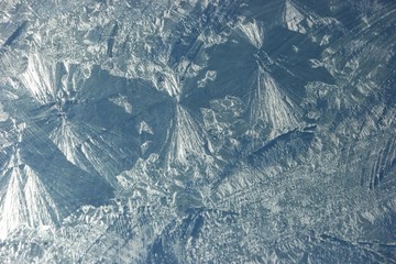 Blue sky through the window glass with frosty patterns, background