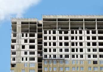 Process of construction high-rise modern apartment building with flat roof and penthouse over blue sky in sunny day horizontal view