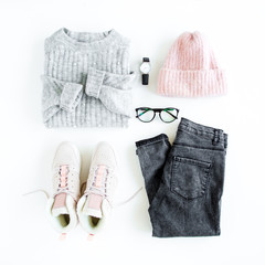 Women fashion clothes and accessories. Feminine youth collage on white background top view. Flat lay female style look with warm sweater, jeans, cap, sneakers, glasses. Top view.