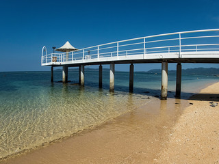 A Long Pier over a Tropical Blue Clear Sandy Beach with No Clouds on Clear Day in Ishigaki, Okinawa Japan
