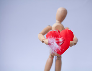 Wood Figure Mannequin holding a red heart on white background
