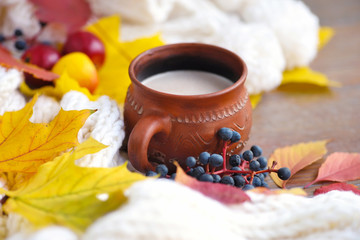 Autumn composition. Cup of coffee, colorful leaves and scarf on wooden background.