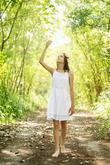 Fototapeta premium Beautiful caucasian preteen girl wearing flower wreath and white dress in forest. Fairy background. Text space
