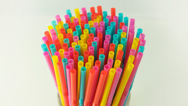 Colorful plastic drinking straws held together against a neutral background. One use, made of plastic straws, number one reason of oceans pollution, harming marine, difficult to biodegrade or dissolve