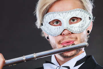 man in carnival mask playing flute