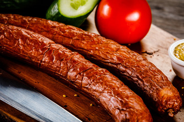 Raw sausages with vegetables on cutting board