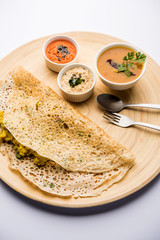 Onion rava masala dosa is a South Indian instant breakfast served with chutney and sambar over moody background. selective focus