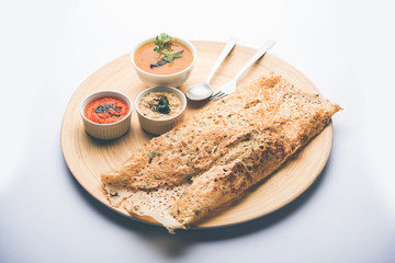 Onion rava masala dosa is a South Indian instant breakfast served with chutney and sambar over moody background. selective focus