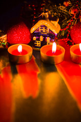 Merry Cristmas. Toy houses and candlelight. Christmas decorations on blurred background. Festive evening. Spruce branches and Christmas toys with bokeh. Copy space