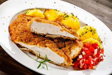 Fried pork chop, boiled potatoes and vegetable salad