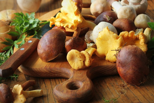Mix of forest mushrooms on cutting board over old wooden table