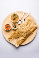 Onion rava masala dosa is a South Indian instant breakfast served with chutney and sambar over moody background. selective focus