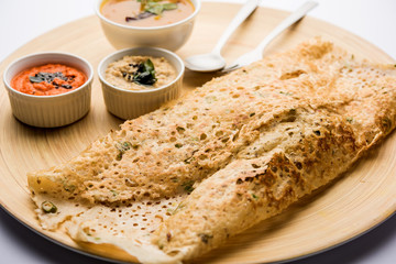 Onion rava masala dosa is a South Indian instant breakfast served with chutney and sambar over moody background. selective focus