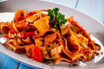 Pasta with tomato sauce and vegtables on wooden table