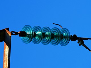 Glass insulators on a power line against a clear blue sky