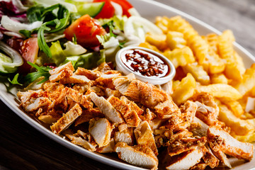 Kebab - grilled meat with french fries and vegetables on wooden background
