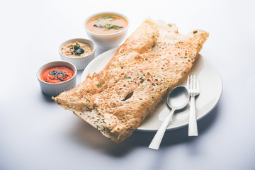 Onion rava masala dosa is a South Indian instant breakfast served with chutney and sambar over moody background. selective focus